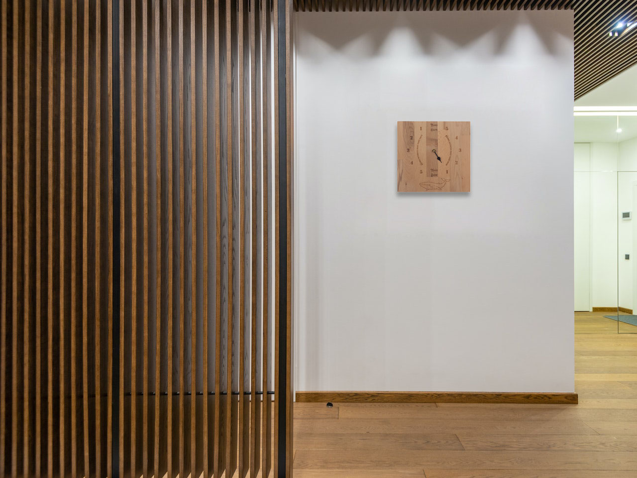 Horloge des marées murale en bois mise en situation sur un mur blanc dans une entrée