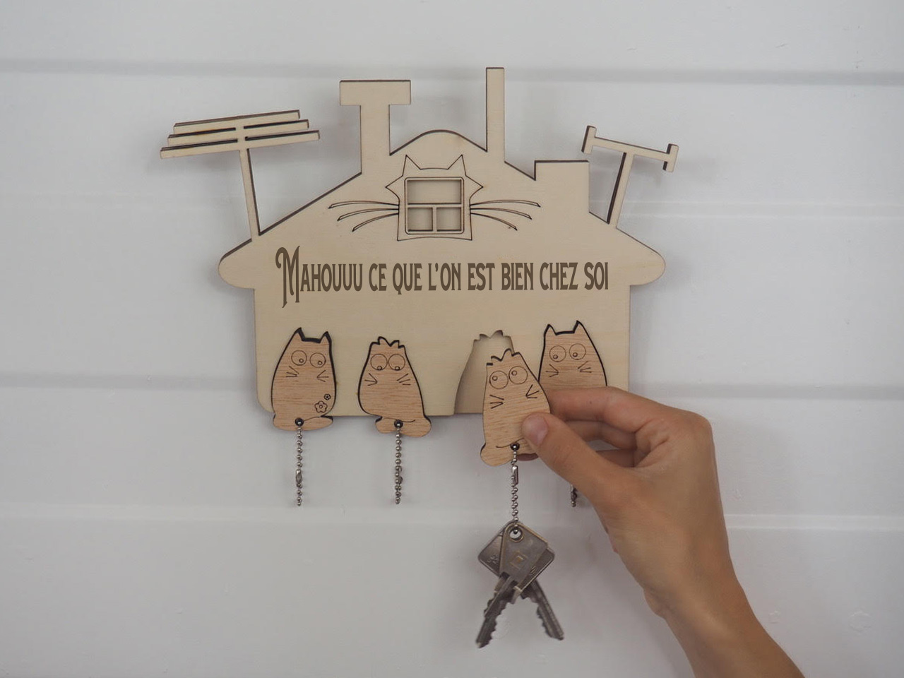 Porte-porte clés chat en bois personnalisable vue avec une main qui prend un des portes clés.
